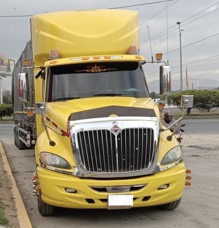 Tracto camión amarillo encendido de noche con luces brillantes, listo para el transporte de materiales reciclables. Un pilar fundamental en la logística del Nuevo Mundo del Reciclaje, impulsando una movilidad sostenible y eficiente.